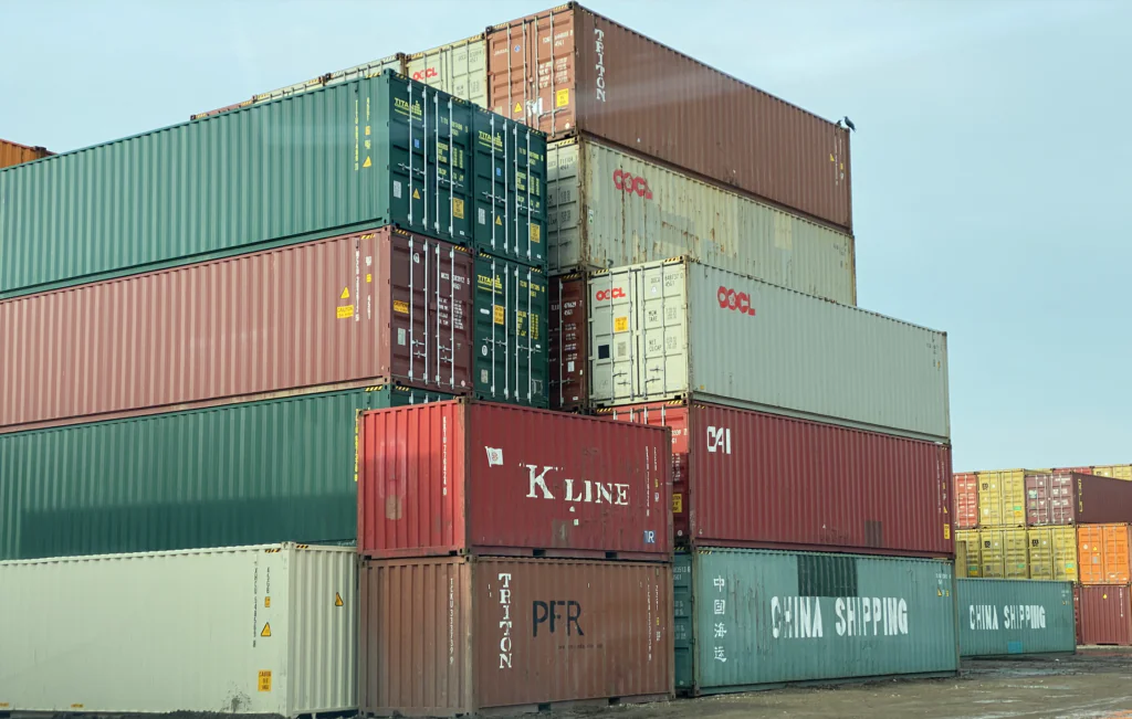 A neatly stacked arrangement of 20' and 40' shipping containers at a depot, featuring both new (one-trip) and used (cargo-worthy) units. The image highlights container availability, durability, and storage capacity.
